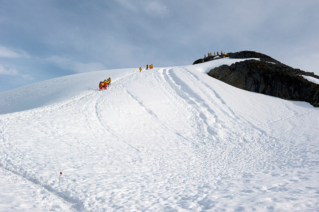 Touristen erklimmen einen gefrorenen Hügel; Antarktis