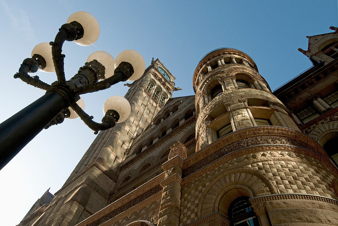 Low Angle View Of A Light Post And A Building With A Clock Tower And A Round Tower; Toronto Ontario Canada