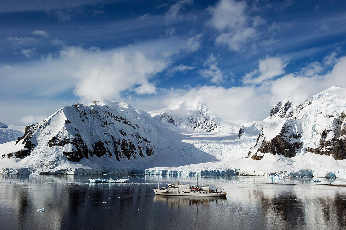 Ein Schiff segelt entlang der Küste; Antarktis