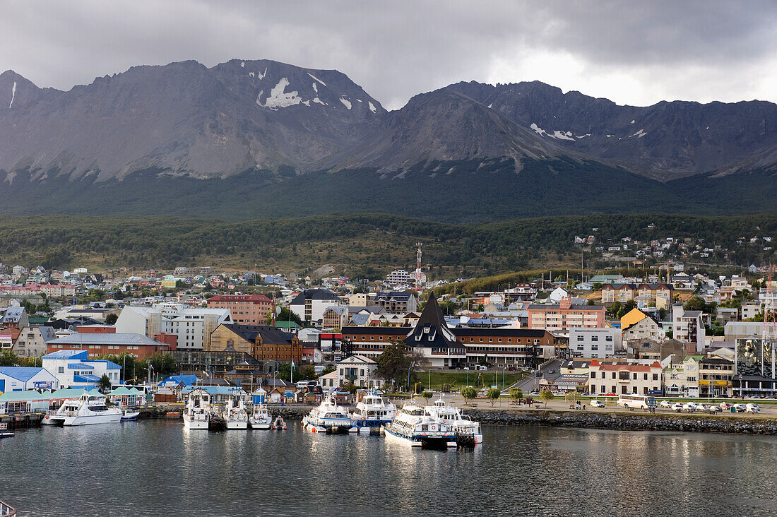 Boats In The Water At The Waterfront Of A City With Mountains In The Background; Ushuaia Argentina