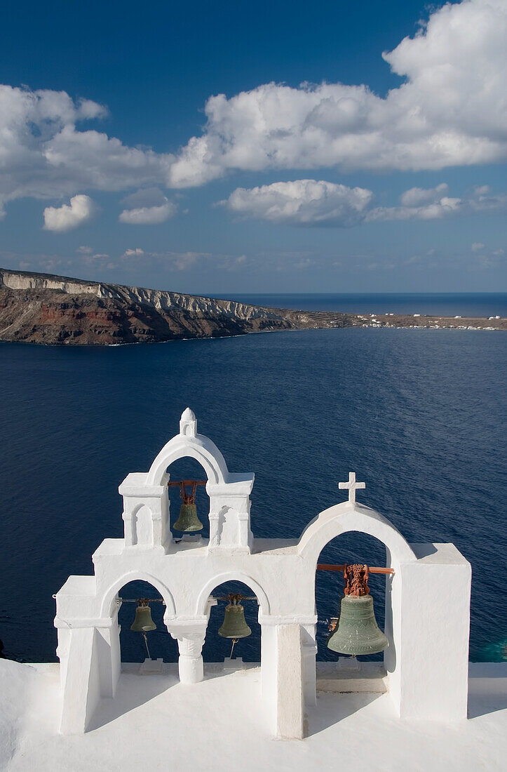 Griechenland, Santorini, Oia, Architektonisches Detail des Glockenturms der griechisch-orthodoxen Kirche, Mittelmeer und die Insel Thirassia in der Ferne.