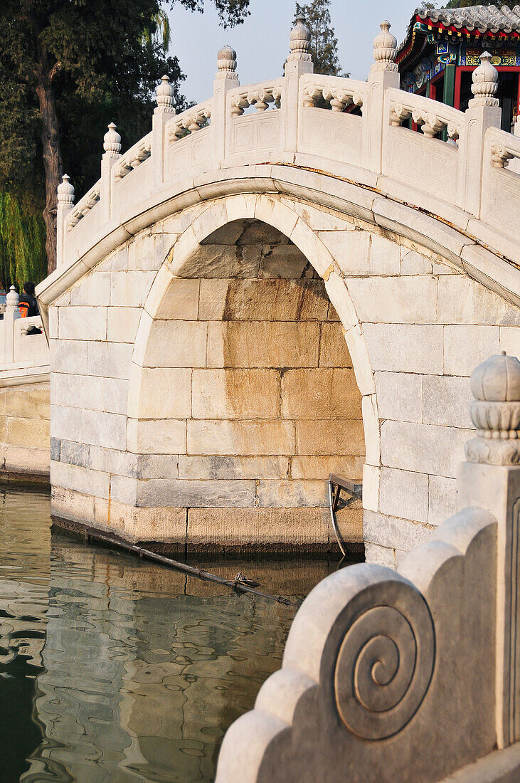 An Arched Bridge With Ornate Railing Going Over Water; Beijing China