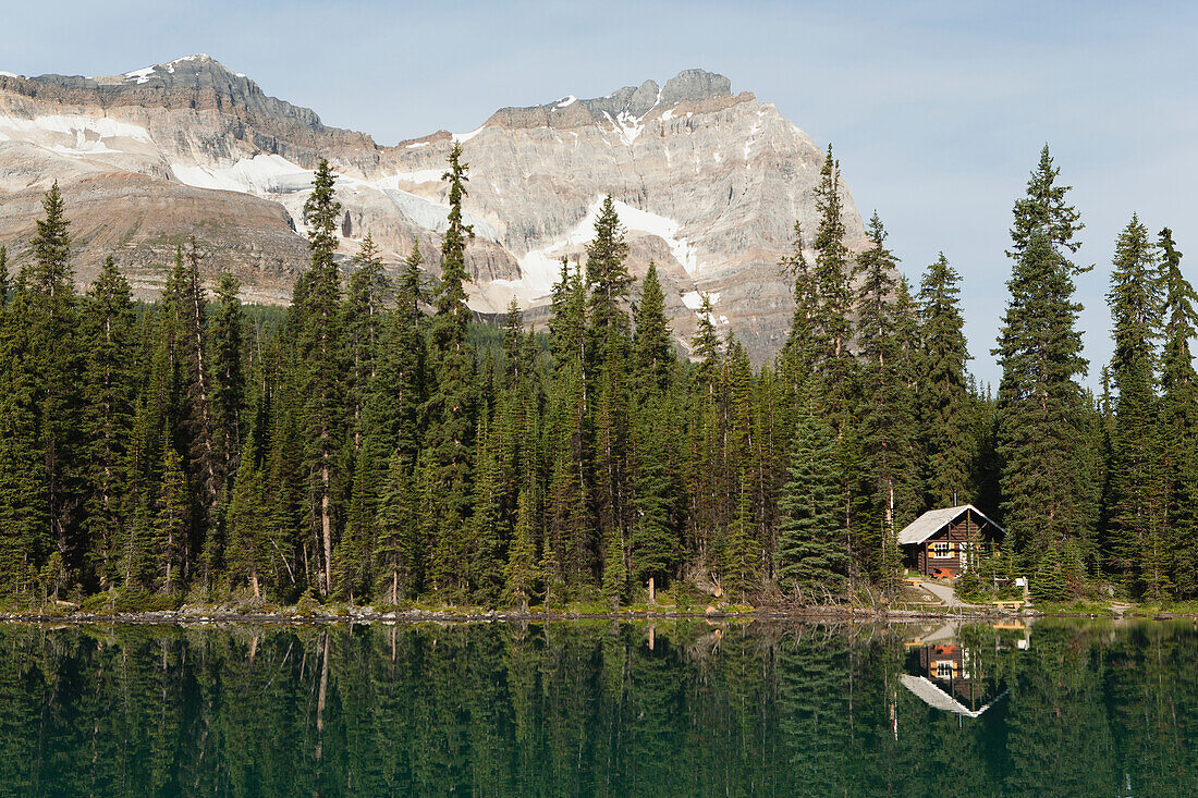 Cabin On Lakeshore Reflecting On Mountain Lake With Mountain In Background; Field British Columbia Canada