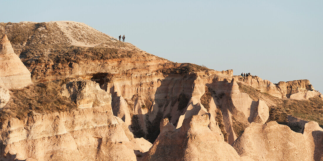 People Standing On The Ridge Of A Rugged Rock Formation; Aktepe Nevsehir Turkey