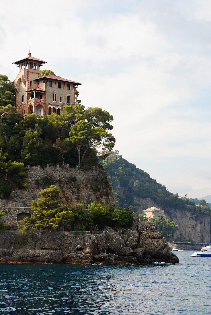 Ein großes Haus auf einer Klippe am Rande des Wassers; Italien