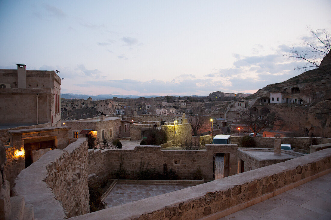 Steinmauern innerhalb einer Gemeinschaft von Häusern mit Lichtern in der Abenddämmerung; Nevsehir Türkei