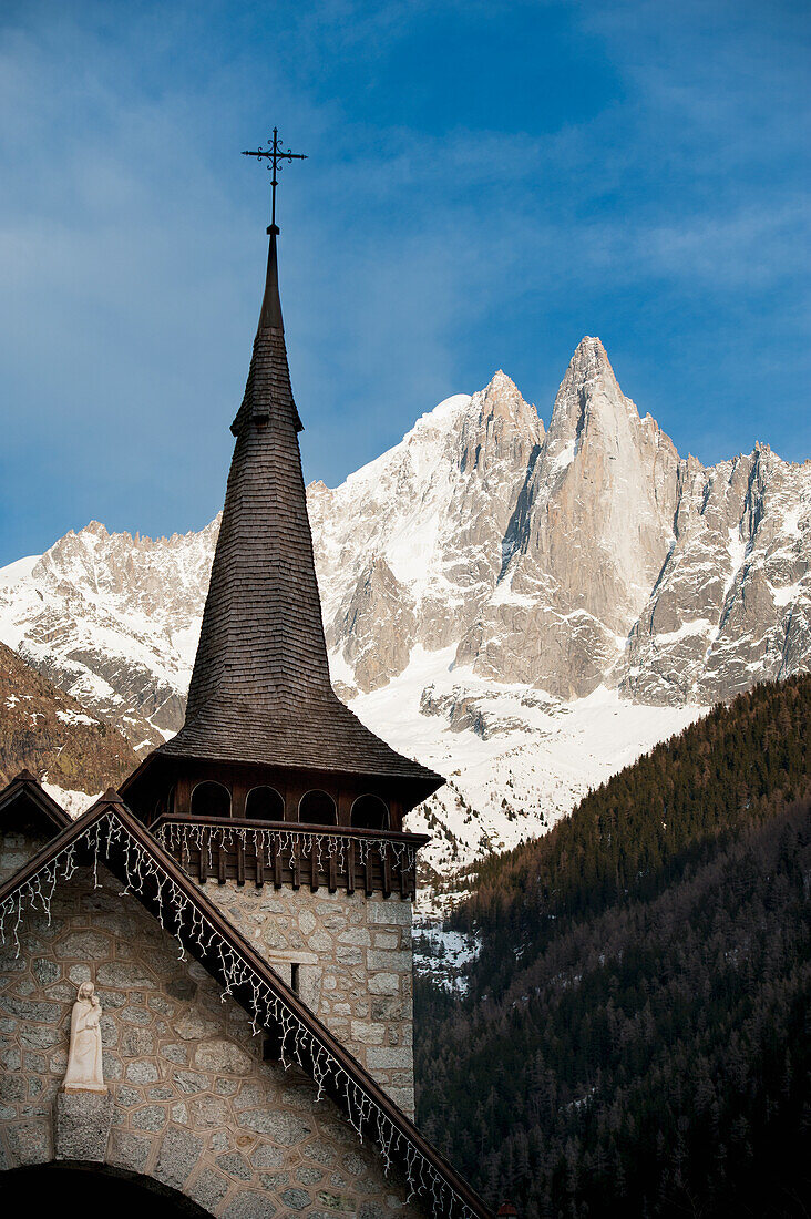 Kirchturm einer Kirche mit Kreuz und Bergen im Hintergrund vor blauem Himmel; Chamonix-Mont-Blanc Rhone-Alpes Frankreich