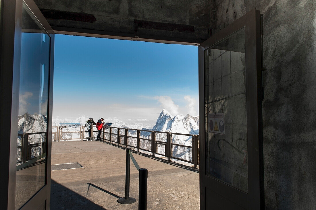 People Peering Over The Edge Of A Railing At The French Alps Mountain Range; Chamonix-Mont-Blanc Rhone-Alpes France
