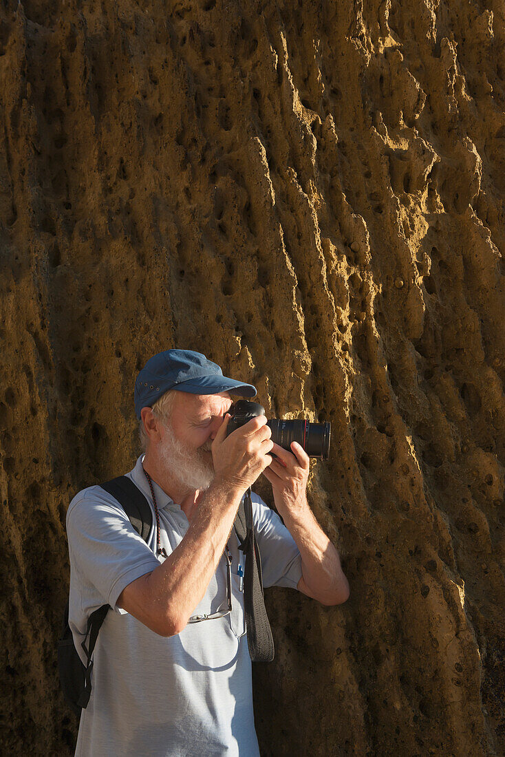 Ein Mann steht an einer Felswand und fotografiert mit seiner Kamera; Andalusien Spanien