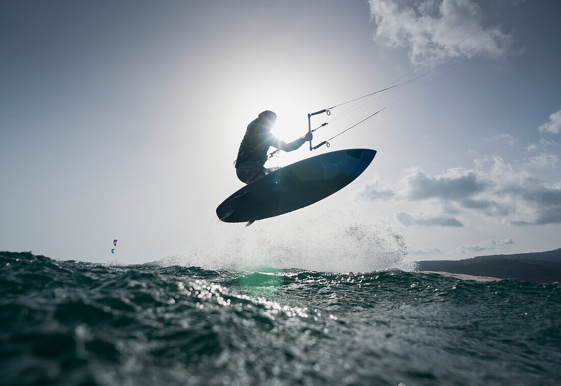 Ein Kitesurfer auf seinem Brett in der Luft; tarifa cadiz andalusien spanien
