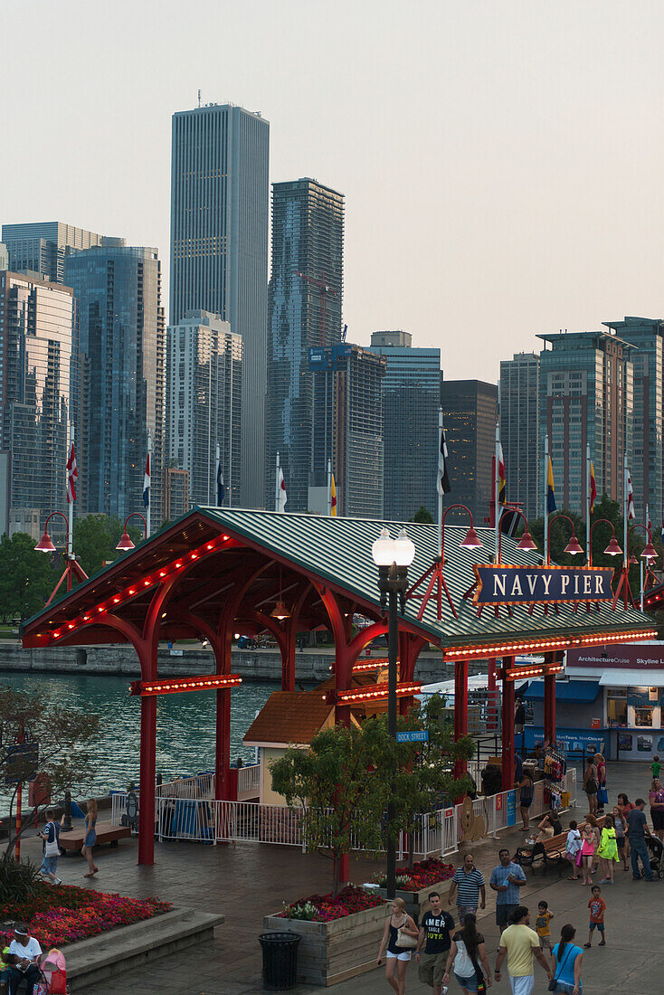 Pedestrians Walking On The Promenade At Navy Pier With Skyscrapers In The Background; Chicago Illinois United States Of America
