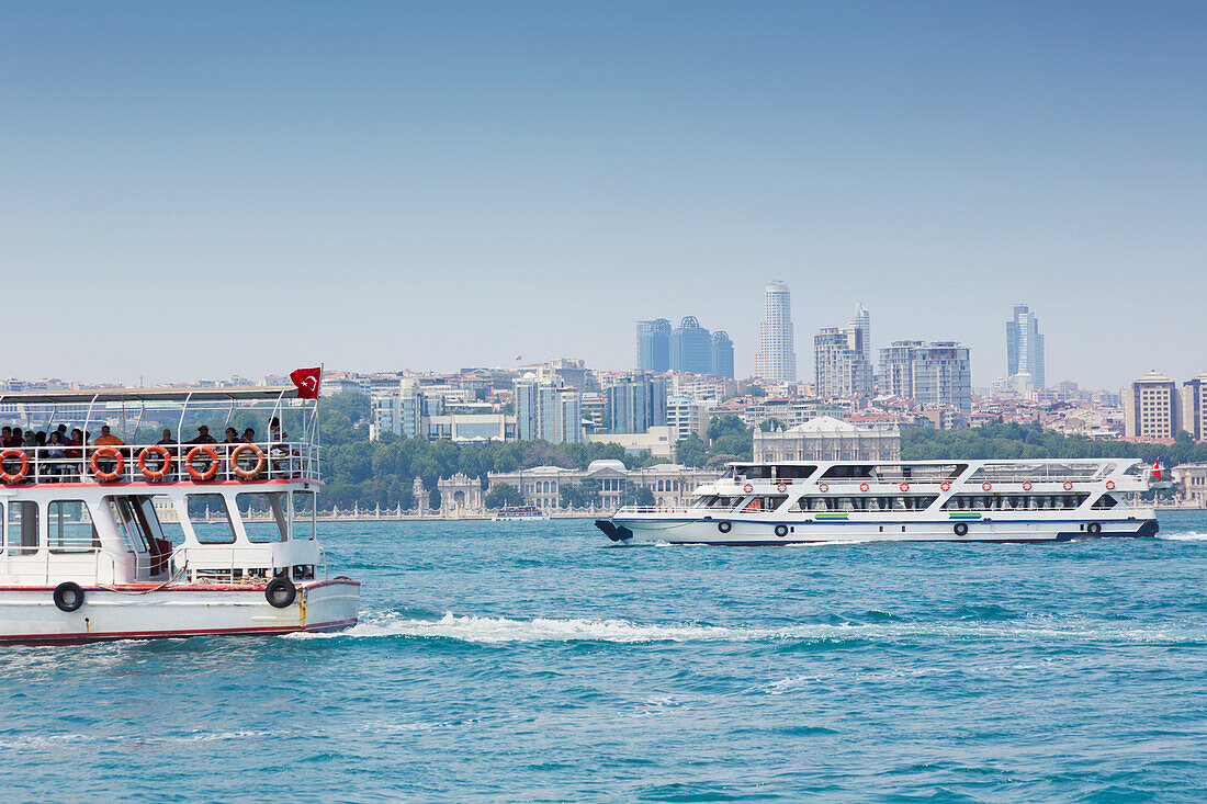 Türkei, Istanbul, Moderne Gebäude an der Stadtsilhouette hinter dem Dolmabahce-Palast mit Bosporus-Fähren im Vordergrund