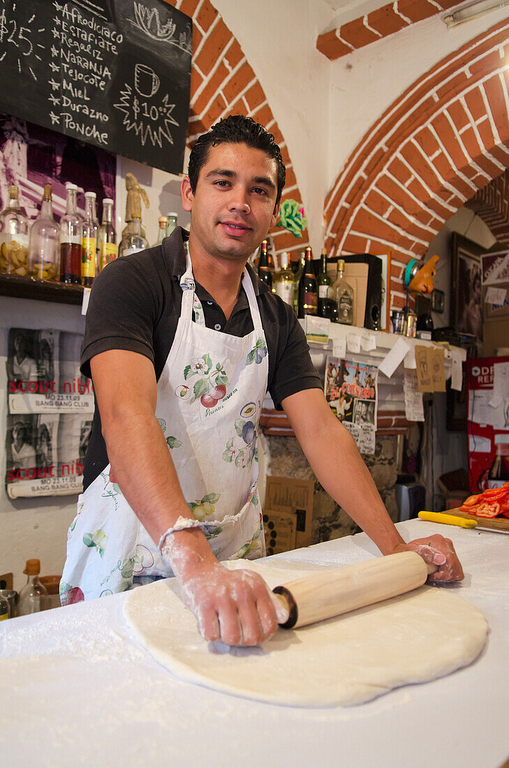 Junger männlicher Bäcker rollt Pizzateig aus; Guanajuato, Bundesstaat Guanajuato, Mexiko