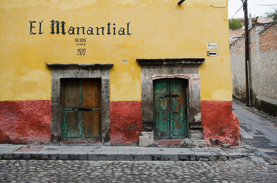 Mexico, Guanajuato, San Miguel de Allende, Front view of building with yellow paint and two wooden gates