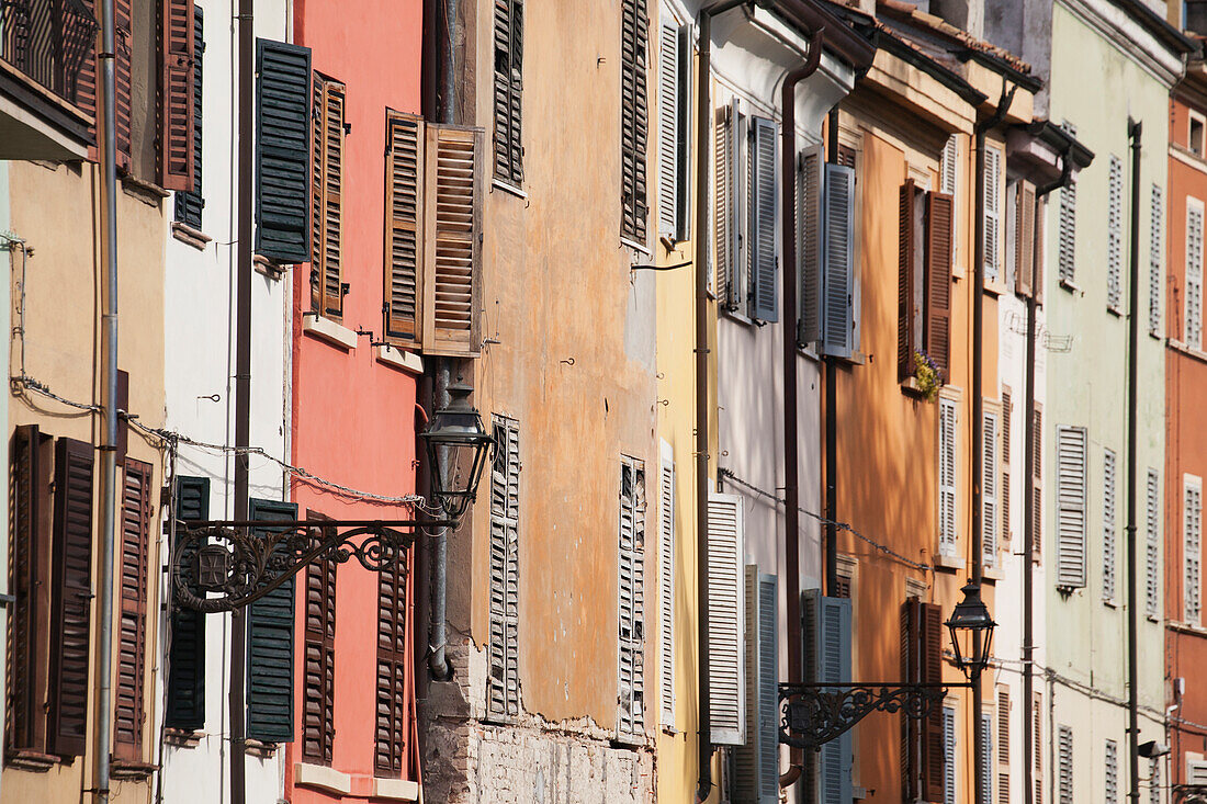 Italien, Emilia-Romagna, Parma, Nahaufnahme von Hausfassaden mit Fensterläden und Straßenlampen