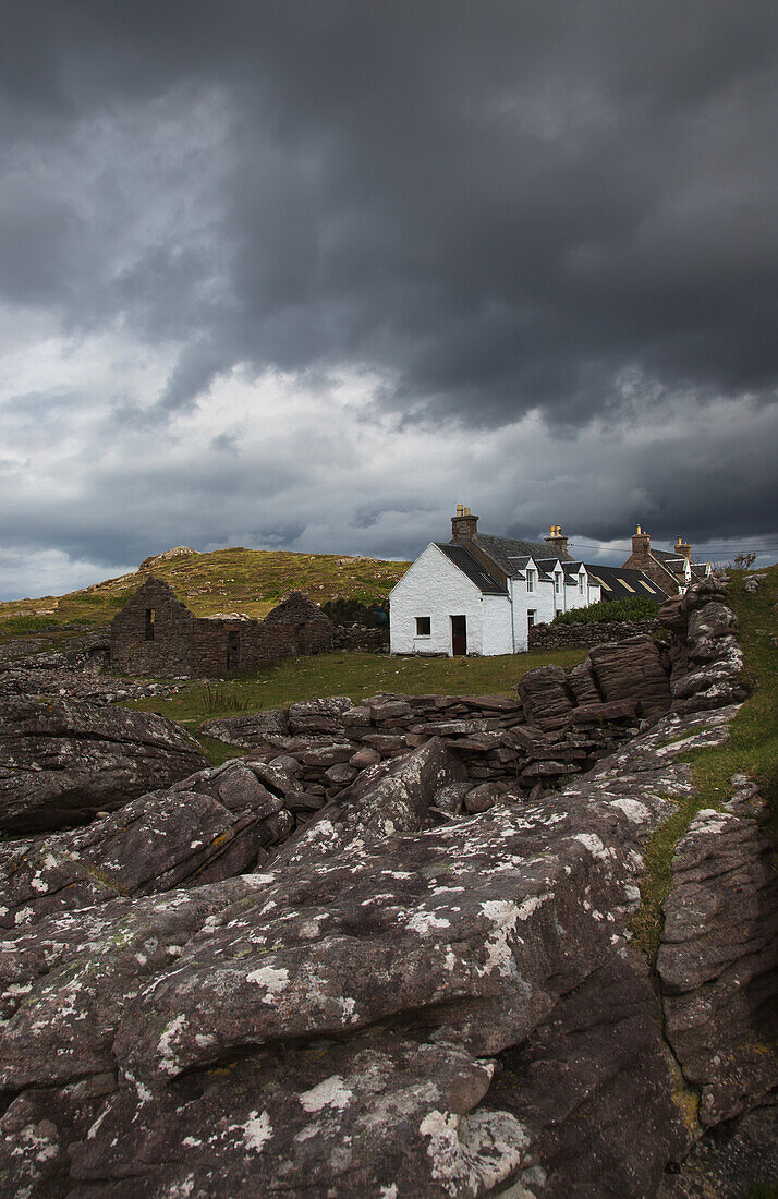 UK, Scotland, Highlands, Applecross Peninsula, Stone wall and cottage houses under stormy sky