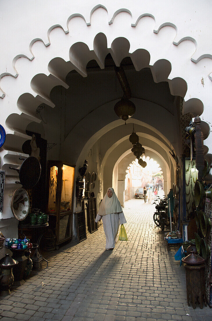 Marokko, Marrakesch, Medina, Frau geht mit Einkaufstasche durch einen überdachten Korridor