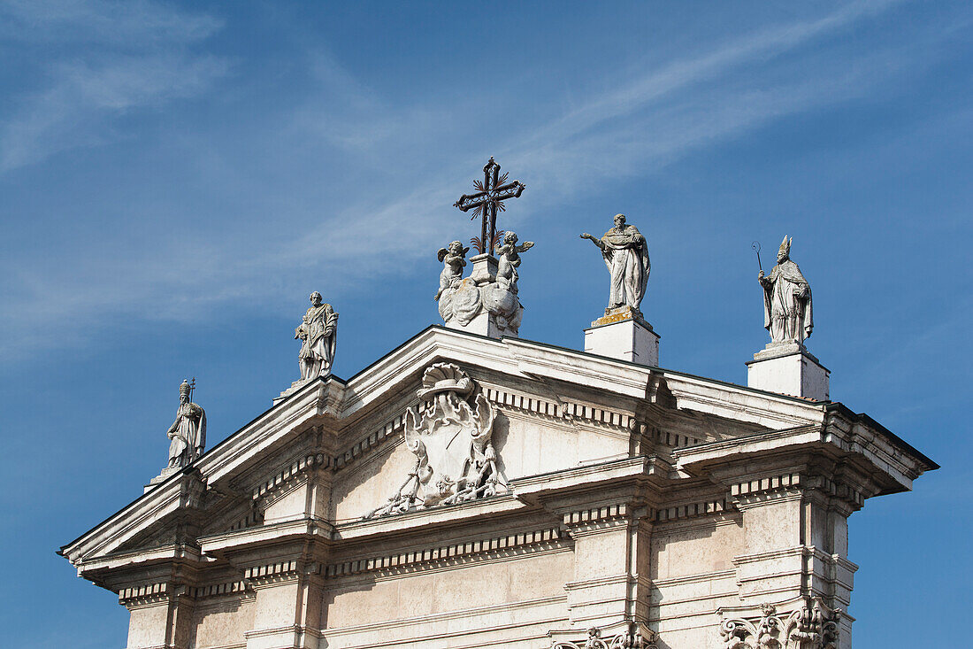 Italy, Emilia-Romagna, Ferrara, Church decoration with statues and cross against blue sky