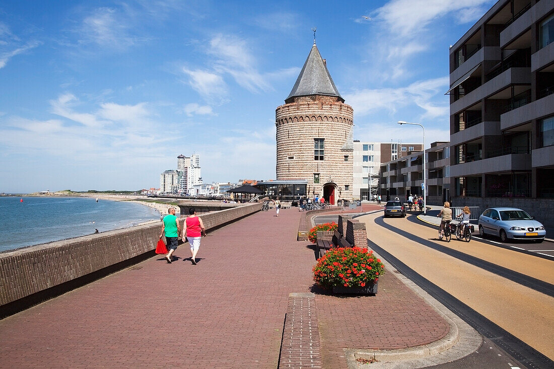 Netherlands, Zealand, Pedestrians walking on promenade along ocean with buildings in town; Vlissingen