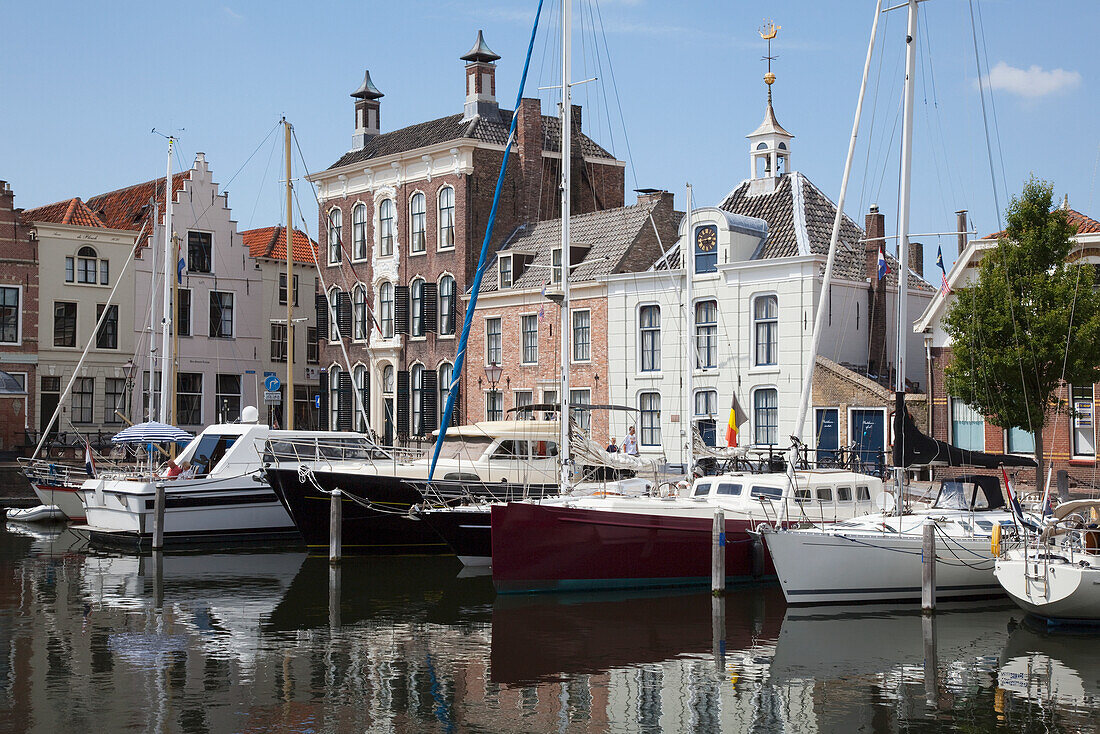 Netherlands, Zealand, Boats in harbour and buildings by waterfront; Goes