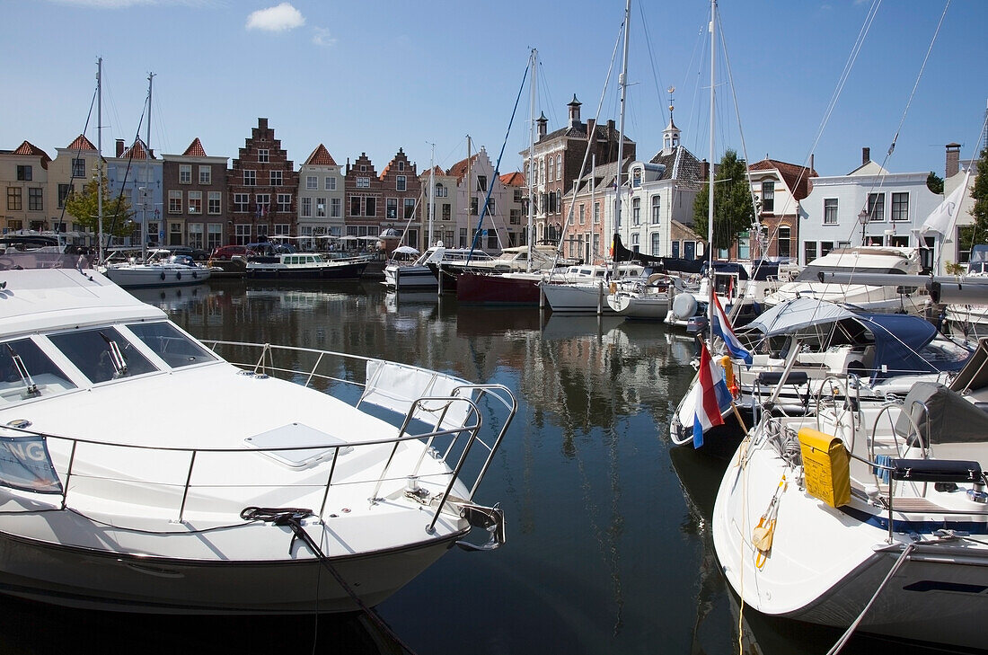 Netherlands, Zealand, Boats in harbour and buildings by waterfront; Goes