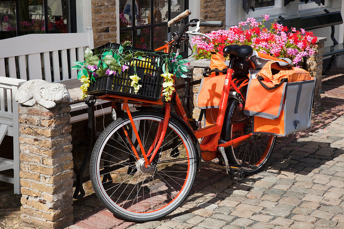 Netherlands, Zealand, Bicycle with attached carrier and basket filled with flowers; Goes