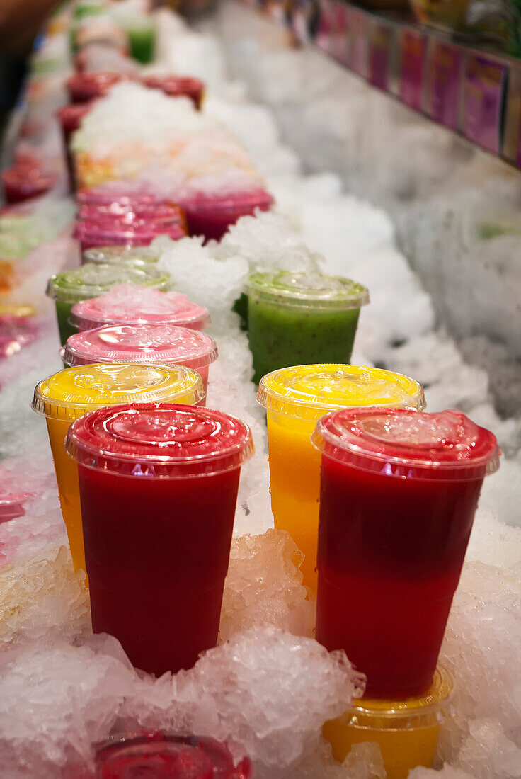 Spain, Catalonia, Cups of fresh fruit juices stacked in crushed ice for sale in La Boqueira; Barcelona