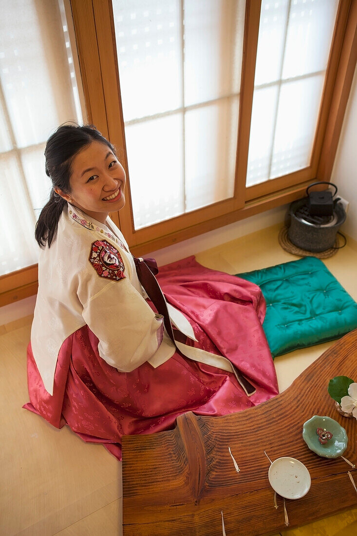Eine Frau sitzt in einem schönen traditionellen Hanbok im Hanok-Dorf Bokchon; Seoul, Südkorea