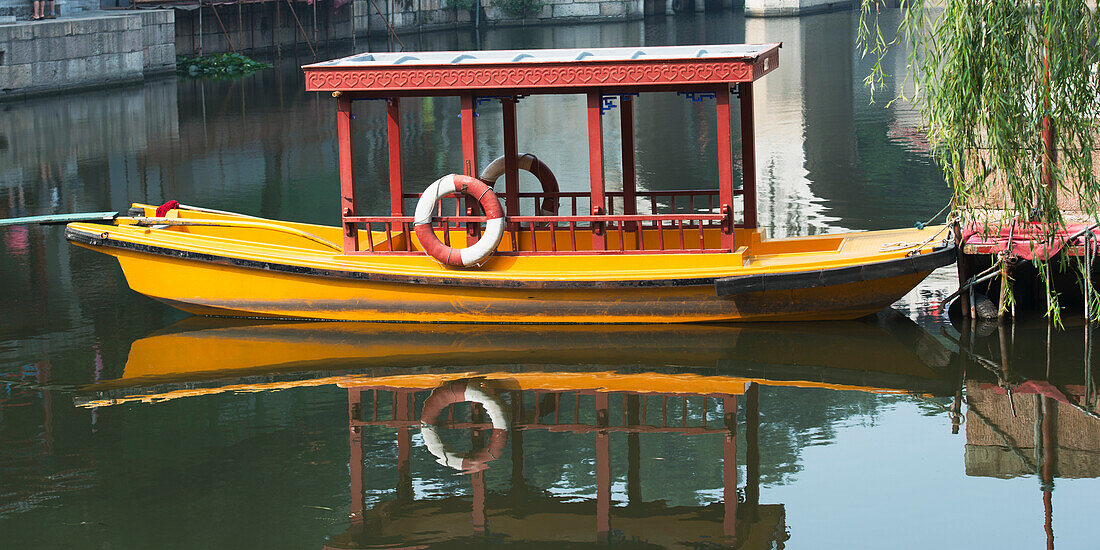 Ein Boot sitzt im ruhigen Wasser an der Küste; Peking, China