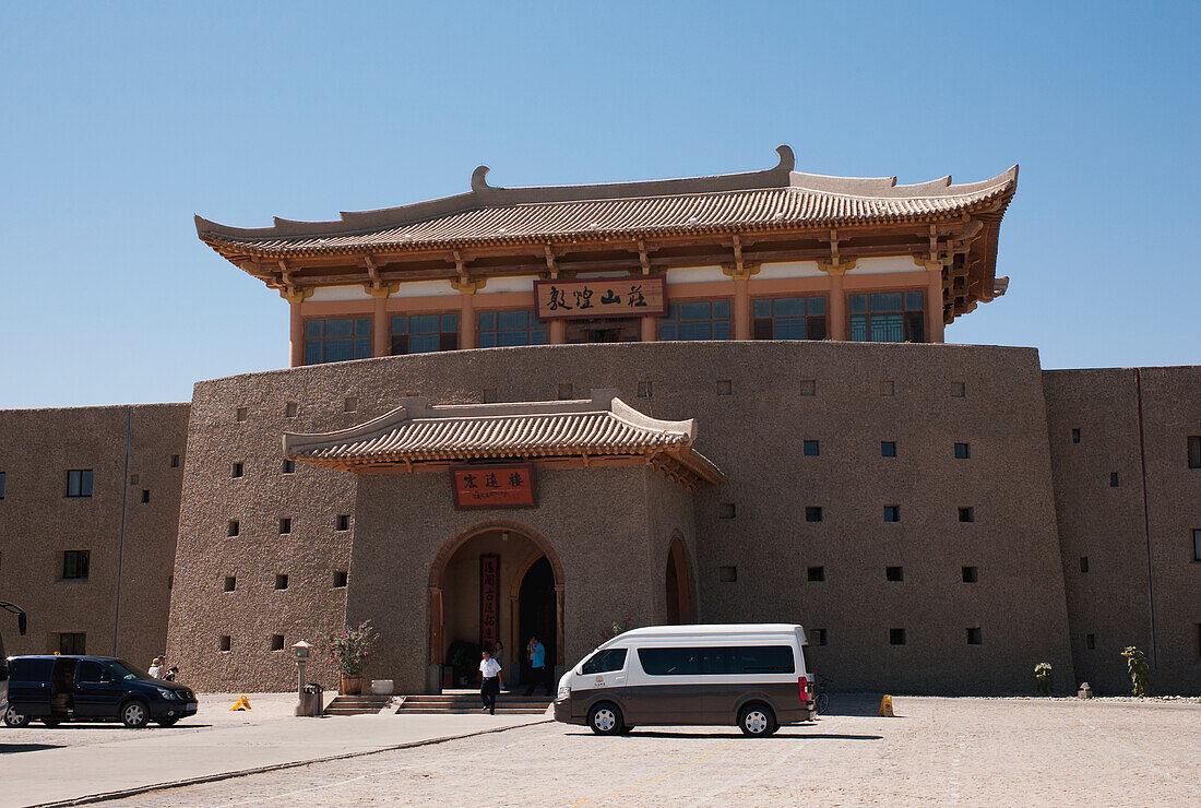 Fahrzeuge parken vor einem Gebäude mit traditioneller chinesischer Architektur; China