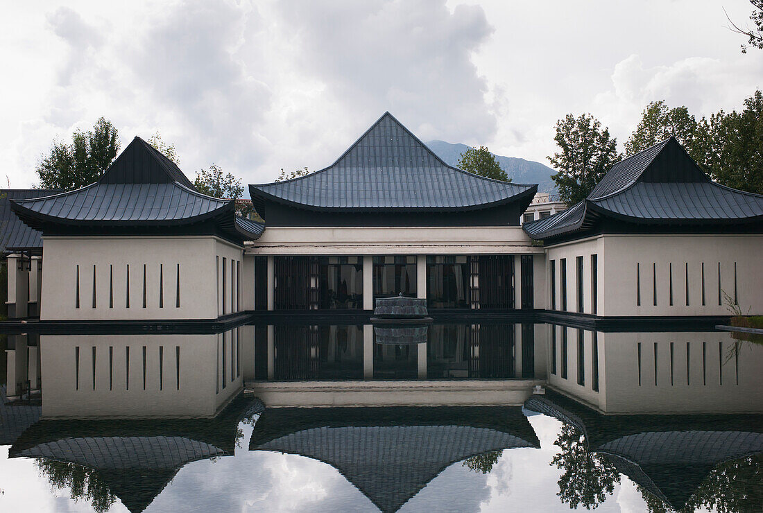 Spiegelbild eines Gebäudes am Wasser, das sich im Wasser spiegelt; China