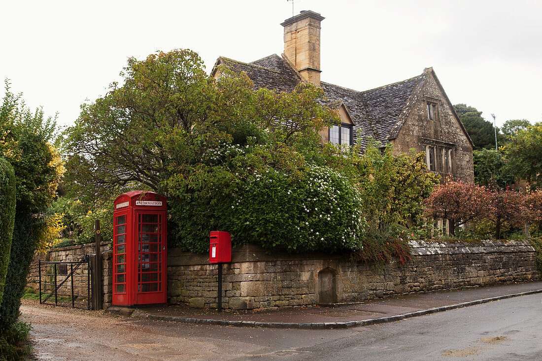 Eine rote Telefonzelle und ein Briefkasten entlang einer Straße; England
