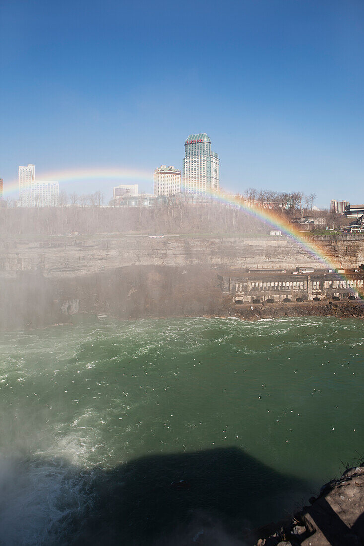 A Rainbow Over Niagara Falls And Gorge With Mist And Blue Sky; Niagara Falls, New York, United States Of America