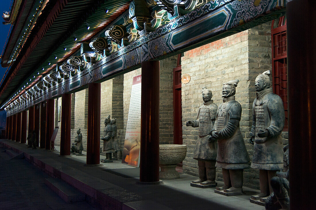 Statuen entlang der beleuchteten Mauer eines Gebäudes bei Nacht entlang der alten Stadtmauer von Lianhu; Xi'an, Shaanxi, China