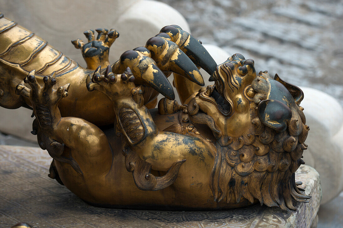 A Gold And Black Sculpture Depicting A Claw Attacking A Smaller Animal; Beijing, China