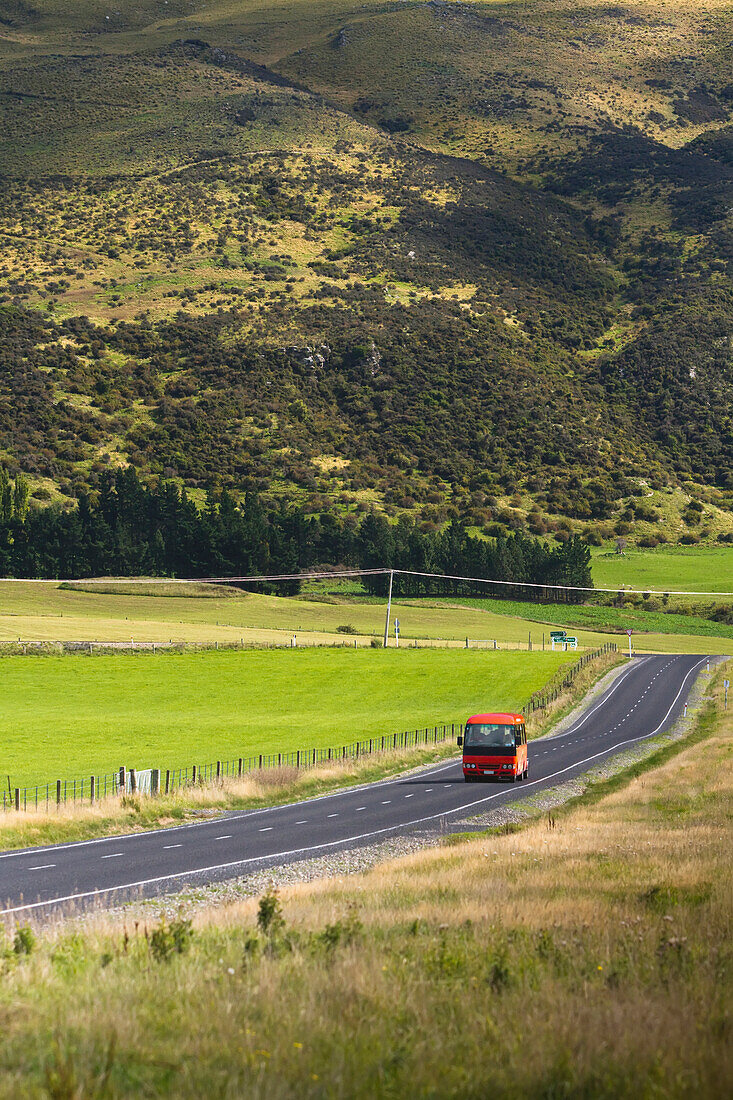 Ein Bus fährt auf einer landschaftlich reizvollen Strecke außerhalb von Hyde in der neuseeländischen Region Otago; Neuseeland