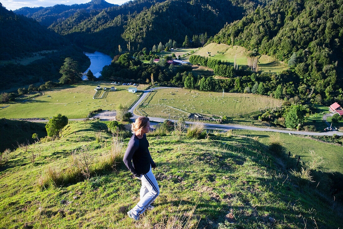 Eine junge Frau bewundert die Aussicht auf das Blue Duck Valley in der Blue Duck Lodge, im Whanganui National Park; Whakahoro, Neuseeland