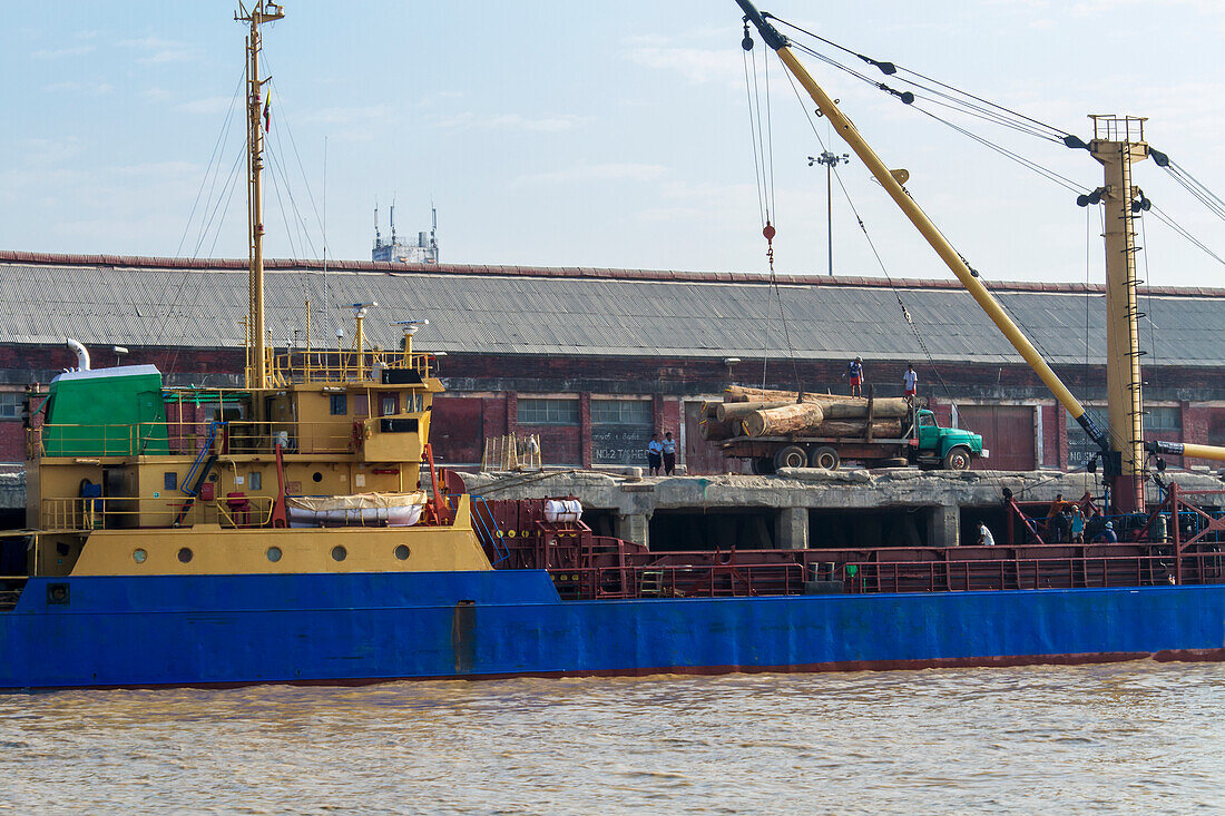 Teakholzstämme werden auf ein Frachtschiff für den Export nach China auf dem Yangon Fluss geladen; Yangon, Myanmar