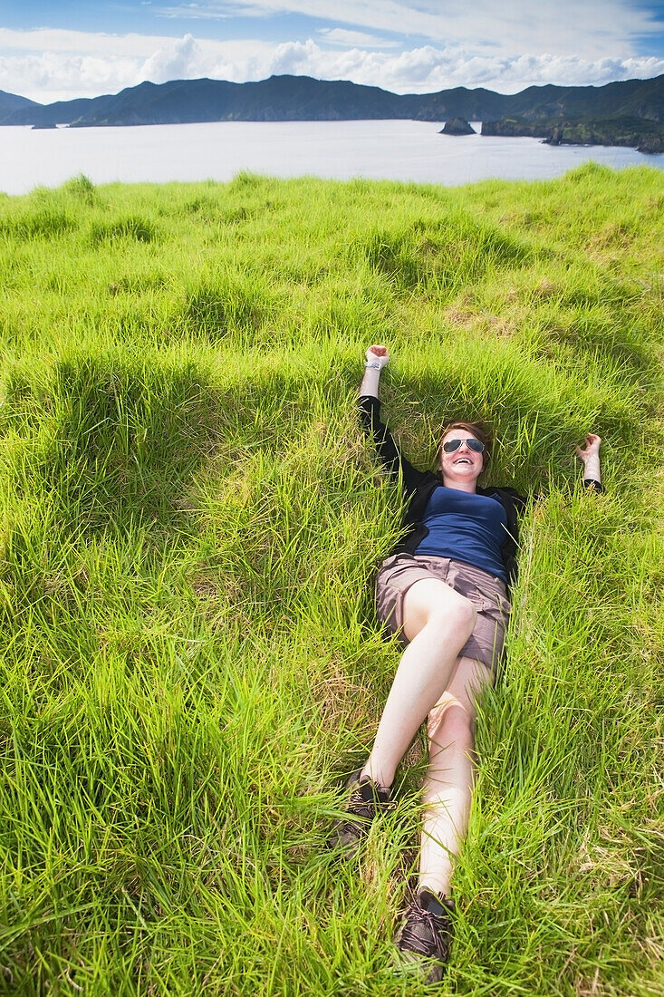 A Girl Relaxes In The Thick Soft Grass On Urupukapuka Island; Bay Of Islands, New Zealand