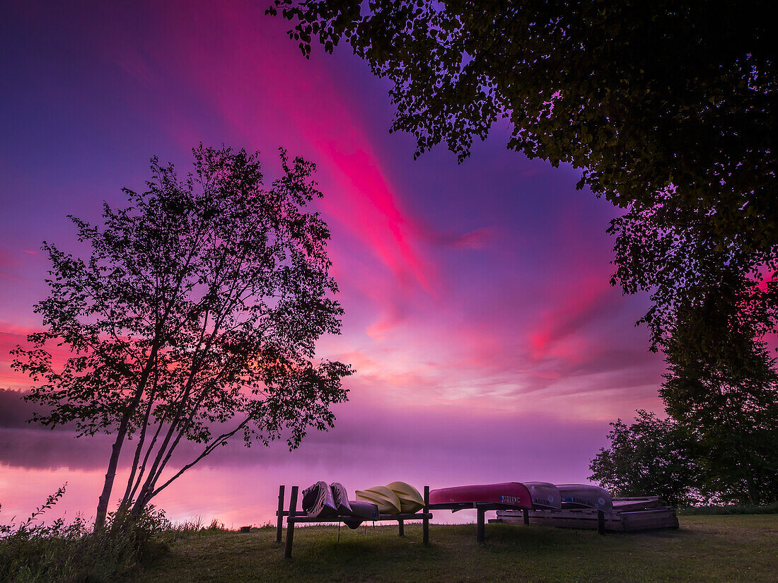 Sunrise Explodes Over Echo Lake In Aroostook State Park With Canoes On The Shore; Presque Isle, Maine, United States Of America