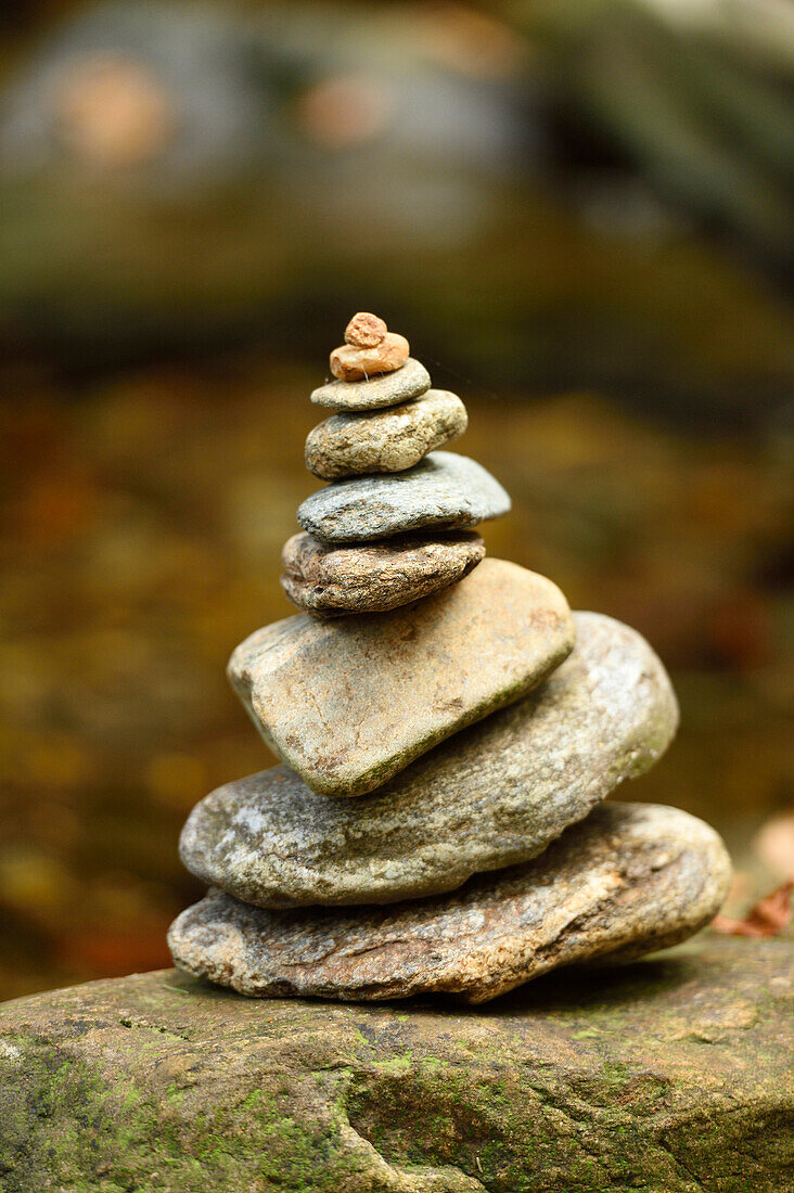 Nahaufnahme eines kleinen Steinhaufens neben einem Fluss im Herbst, Nationalpark Bayerischer Wald, Bayern, Deutschland