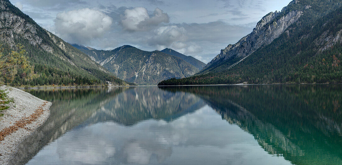 Landschaftliche Ansicht von Bergen, die sich in einem klaren See (Plansee) im Herbst spiegeln, Tirol, Österreich