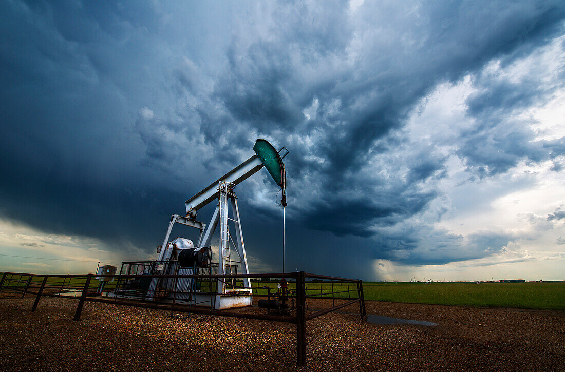 Pump jack, oil well, in field with stormy sky, Canadian praires, Saskatchewan, Canada