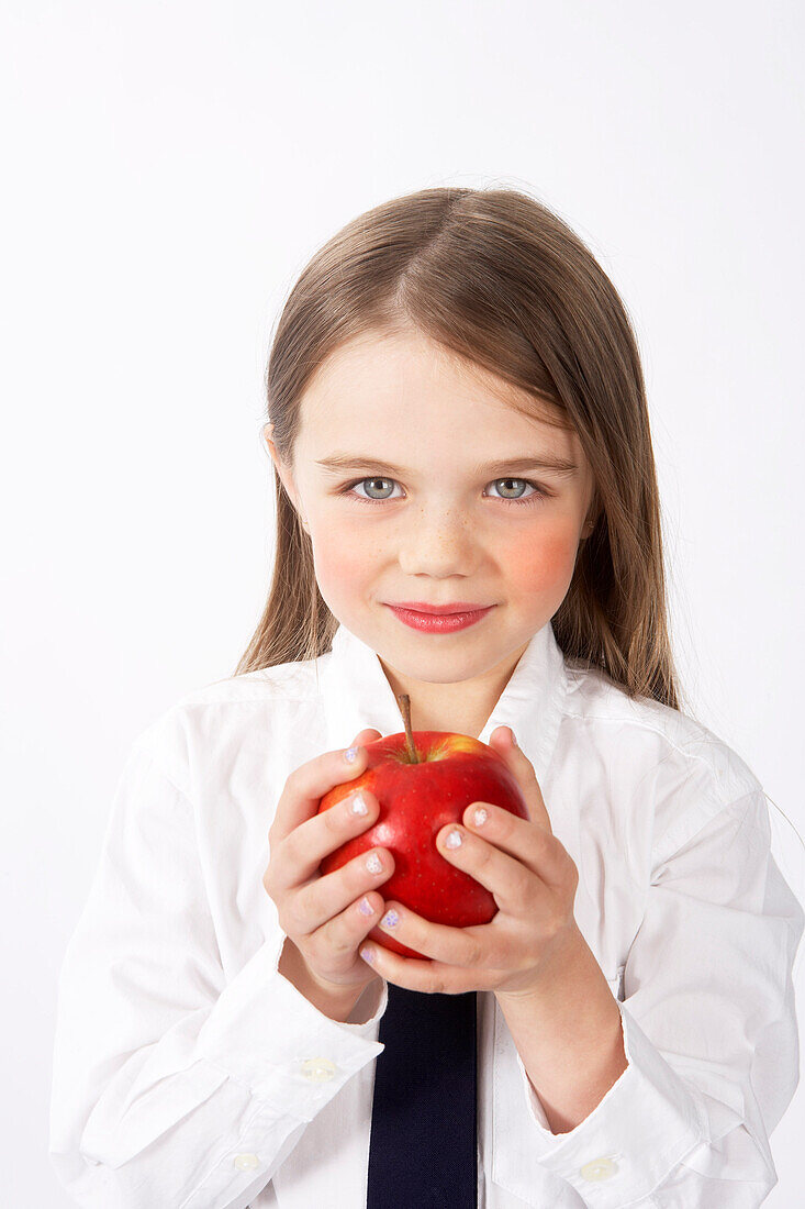Mädchen in Schuluniform hält Apfel