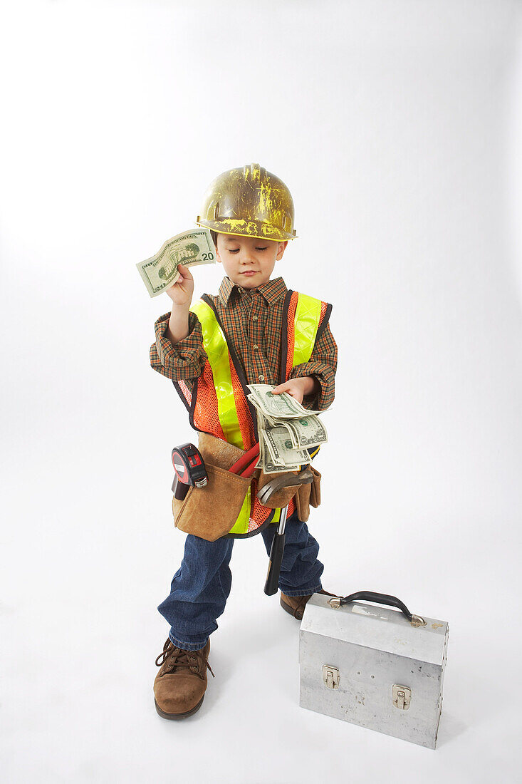 Junge, verkleidet als Bauarbeiter, hält Geld