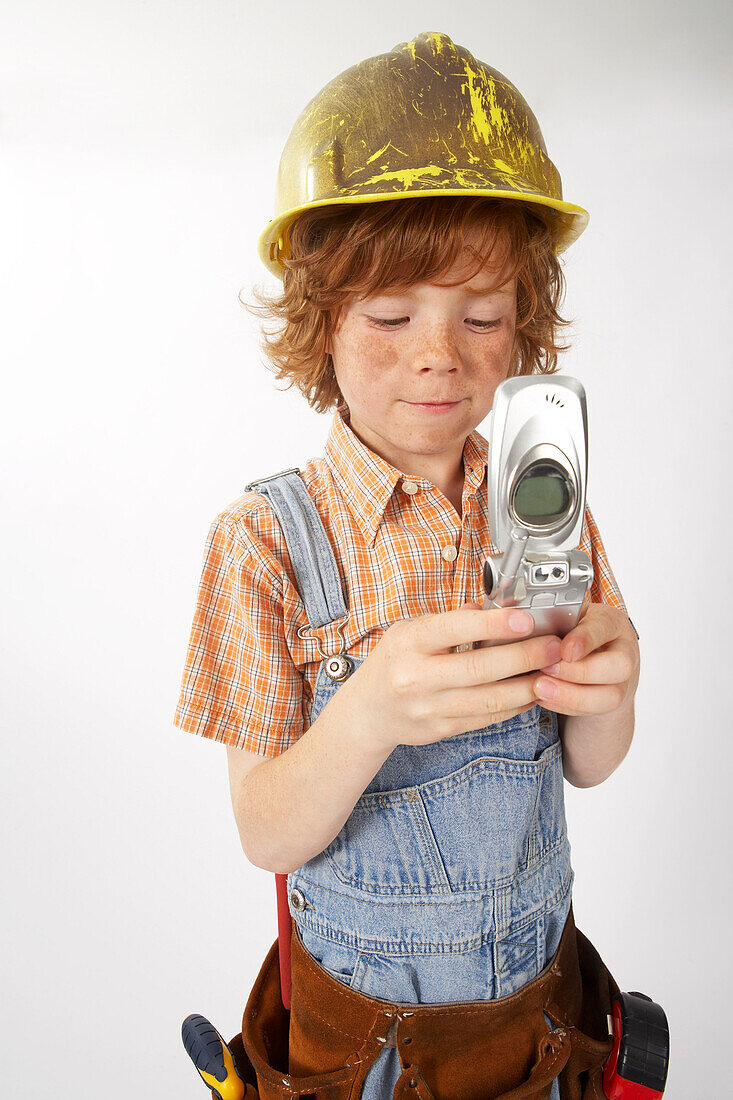Junge als Bauarbeiter verkleidet benutzt Handy