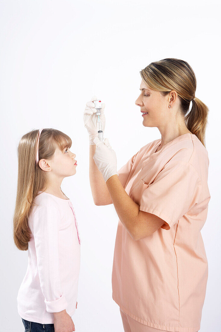 Kleines Mädchen sieht Krankenschwester beim Vorbereiten einer Nadel zu