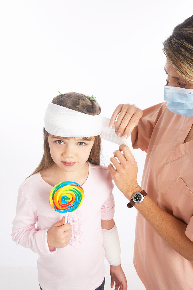 Krankenschwester wickelt Verband um den Kopf eines Mädchens