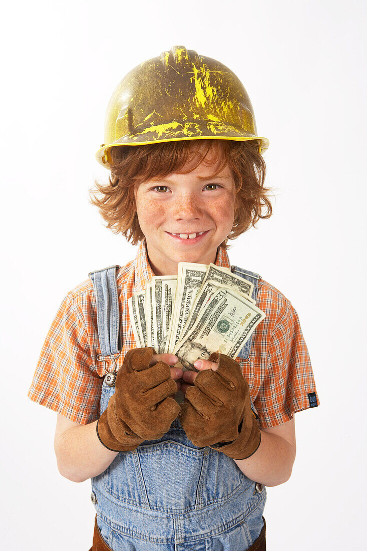 Kleiner Junge, verkleidet als Bauarbeiter, hält Bargeld