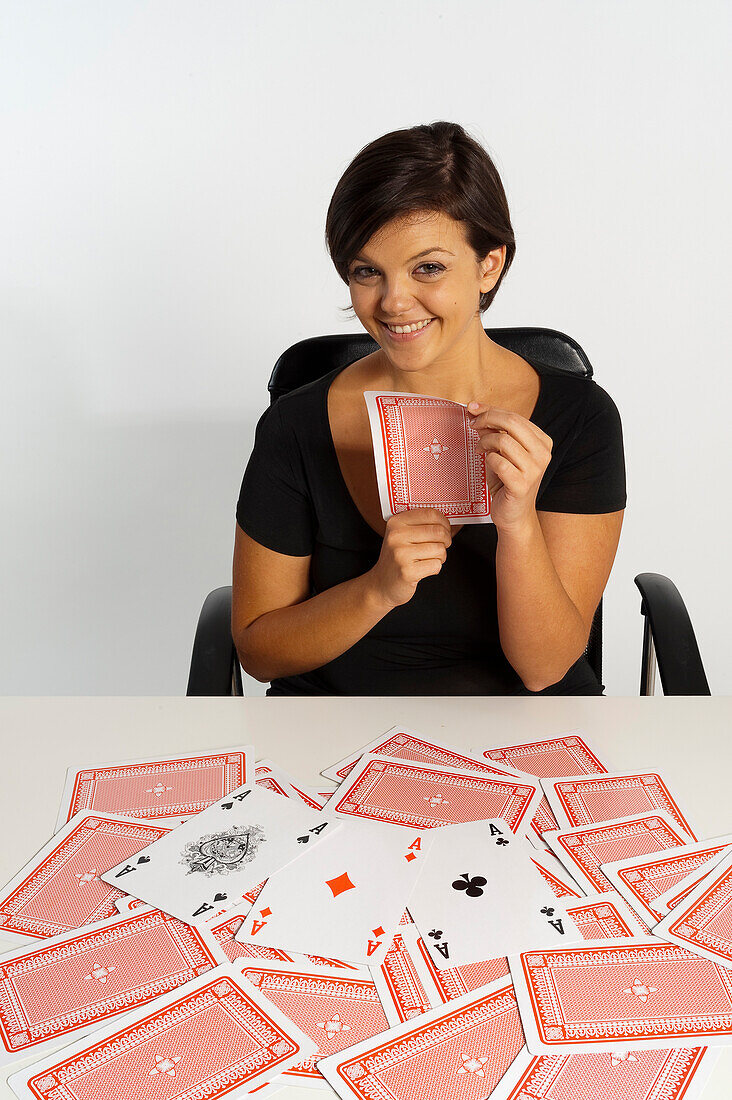Mittlere erwachsene Frau macht Zaubertrick mit Kartenspiel